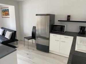 uma cozinha com um frigorífico de aço inoxidável e um micro-ondas em Antheor cap Roux em Saint-Raphaël