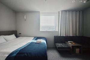 een slaapkamer met een bed, een stoel en een raam bij Hotel Rakuragu in Tokyo