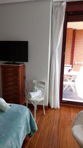 ein Schlafzimmer mit einem Bett, einem TV und einem Stuhl in der Unterkunft Apartamento en la playa con parking privado in Getxo