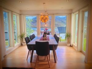 a dining room with a table and chairs and windows at Sørvågen Villa luxury home with sauna in Sørvågen