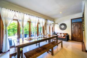 una sala da pranzo con un lungo tavolo e un divano di Villa SANKET - KUTA - 6 bedrooms - 6 bathrooms - Great Location a Kuta