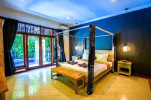 Villa SANKET - KUTA - 6 bedrooms - 6 bathrooms - Great Location في كوتا: غرفة نوم بسرير مظلة ومقعد