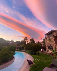 a pool in a yard with a sunset at Hôtel Ambassador Palombaggia in Porto-Vecchio