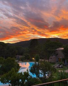 a sunset over a swimming pool at a resort at Hôtel Ambassador Palombaggia in Porto-Vecchio