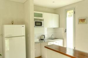 a kitchen with white cabinets and a white refrigerator at Las Camelias Apart in Chascomús