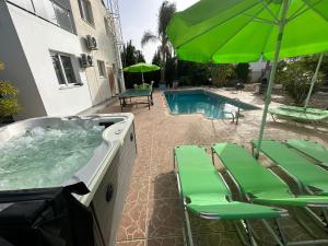 a hot tub with lawn chairs and an umbrella at Villa Coralia Gardens 1km From Coral Bay Beach in Coral Bay