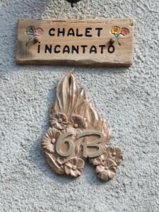 un signo que lee el encantamiento del chatelino y una flor en una pared en Chalet del paese Incantato, en Moncenisio