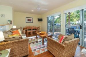 a living room with wicker furniture and a dining room at Point Break in Boomerang Beach