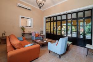 a living room with an orange couch and blue chairs at Espectacular casona con alberca y jardines in Mérida