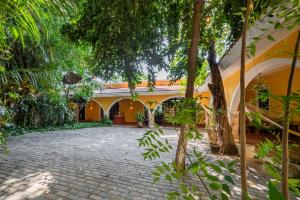 a courtyard of a house with trees and a brick driveway at Espectacular casona con alberca y jardines in Mérida