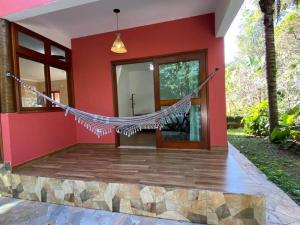 a red house with a hammock in front of it at Ycatu Beach House in São Sebastião