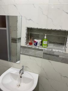 a white bathroom with a sink and a mirror at Melford Homes in Lagos
