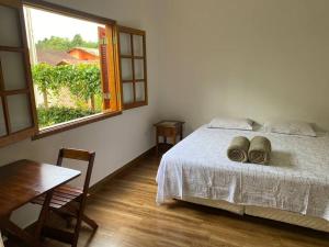 1 dormitorio con cama, mesa y ventana en Ycatu Beach House, en São Sebastião