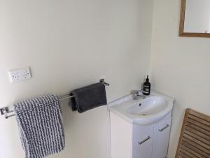 a white bathroom with a sink and a towel at Large garden block with multiple dwellings in the centre of Bendigo in Bendigo