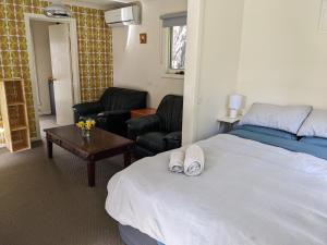 a bedroom with a bed and a living room with chairs at Large garden block with multiple dwellings in the centre of Bendigo in Bendigo