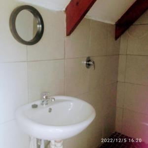 y baño con lavabo blanco y espejo. en Room in BB - Zagorskis Bb Lovely room with balcony, en Ciudad del Cabo