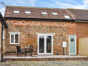 una casa de ladrillo con una mesa y sillas en un patio en The Hay Barn-uk41602 en Stainton