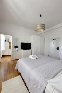 a white bedroom with a large bed and a flat screen tv at Apartments Miljas 2 in Dubrovnik