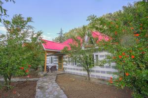 una casa con techo rojo y algunos árboles en SaffronStays The Elements, en Kulu