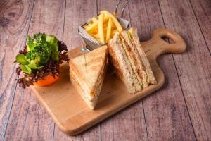 a sandwich and french fries on a wooden cutting board at Holiday Inn Al Khobar - Corniche, an IHG Hotel in Al Khobar