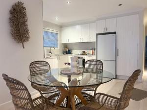 a dining room with a glass table and chairs at Soulshine Beachside Penthouse in Surf Beach