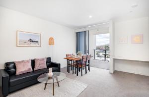 ein Wohnzimmer mit einem schwarzen Sofa und einem Tisch in der Unterkunft Brandnew Spacious and Stunning 1bed Apartment in Brisbane