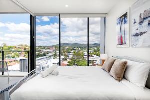 a bedroom with a large white bed and large windows at Brandnew Spacious and Stunning 1bed Apartment in Brisbane