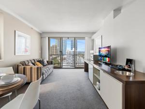 a living room with a couch and a table with a tv at Amazing suite with beach views at prime location in Gold Coast