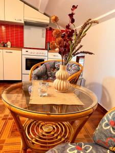 a glass table with a vase with flowers on it at Apartments Zukanovic in Fažana