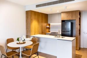 La cuisine est équipée d'une table, de chaises et d'un réfrigérateur. dans l'établissement Brand New Riverside Designer 2BD apartment at West End, à Brisbane
