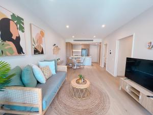 a living room with a blue couch and a flat screen tv at Brand New Riverside Designer 2BD apartment at West End in Brisbane