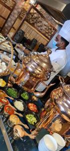 a chef standing in a kitchen preparing food at Golden Tulip Al Khobar in Al Khobar