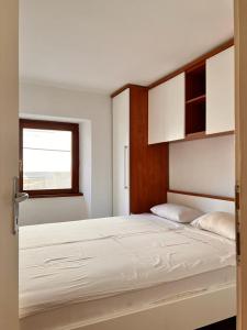 1 dormitorio con 1 cama grande con sábanas blancas en Apartments Zukanovic, en Fažana