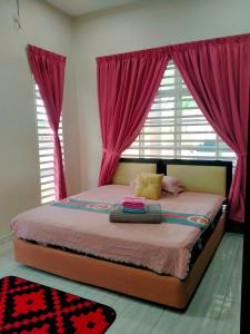 Homestay Haji Din Tronoh Perak في Teronoh: غرفة نوم مع سرير مع ستائر وردية ونافذة