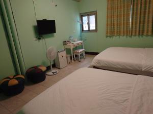 a bedroom with two beds and a desk and a television at 里山旅棧民宿 Li Shan Homestay in Fuli