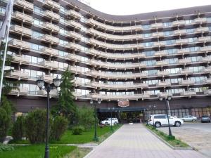 un gran edificio con coches estacionados frente a él en Premier Alatau Hotel, en Almaty