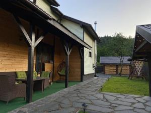 a covered patio with a couch and chairs next to a house at Mountain Residence in Tukhlya