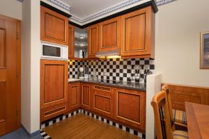 a kitchen with wooden cabinets and black and white tiles at MONDI Hotel Bellevue Gastein in Bad Gastein