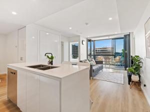 a kitchen with white cabinets and a living room at Heart of the Valley Chic High Level 2BR Apartment in Brisbane