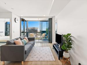 a living room with a couch and a tv at Heart of the Valley Chic High Level 2BR Apartment in Brisbane