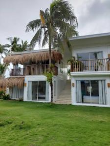 a house with a palm tree in front of it at Sea Green Boutique Rooms in General Luna