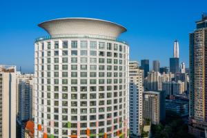Blick auf ein hohes weißes Gebäude in einer Stadt in der Unterkunft Jingju Hotel Shenzhen in Shenzhen
