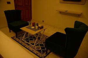 GO Luxury Grand Hotel في لاهور: غرفة معيشة مع كرسيين وطاولة