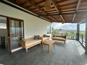a porch with benches and a table on a balcony at Agusta Lake View Bedugul in Pabean Buleleng