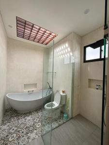 a bathroom with a tub and a toilet and a shower at Agusta Lake View Bedugul in Pabean Buleleng