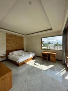 a bedroom with a bed and a desk and a window at Agusta Lake View Bedugul in Pabean Buleleng