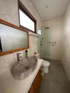 a bathroom with a stone sink and a toilet at Agusta Lake View Bedugul in Pabean Buleleng