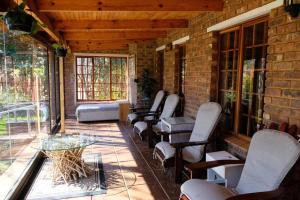 a screened porch with chairs and a glass table at Eden Rain in Dullstroom