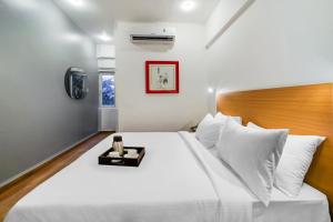 a bedroom with a large white bed with a wooden headboard at Townhouse De Alphabet Tirupati in Tirupati
