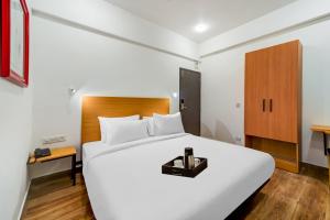 a bedroom with a white bed and a cabinet at Townhouse De Alphabet Tirupati in Tirupati